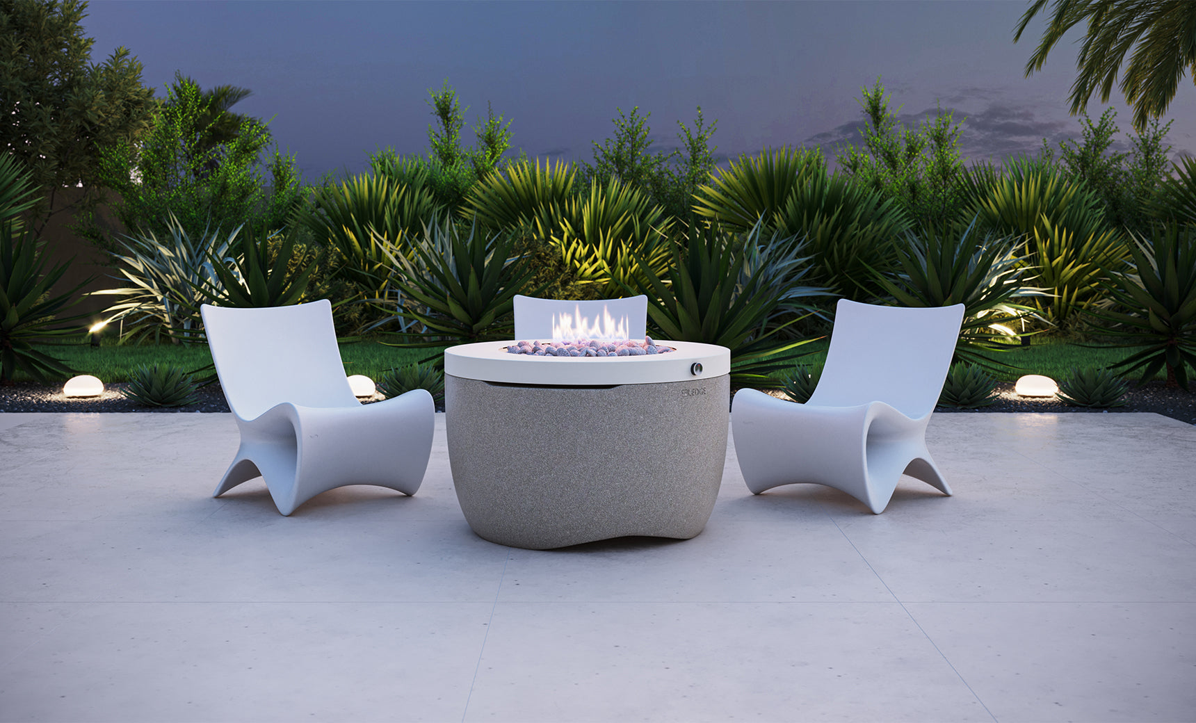 Three white, curved chairs are arranged around the Halo Firepit by Ledge Lounger on a light stone patio. The fire pit features a pivot-glide lid and emits a small flame, while lush green plants and soft ground lights decorate the background.