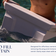 A person stands in a pool holding the Ledge Lounger Signature Chaise Armrest Console, partially submerged. It features easy filling and maintenance, with clear care instructions included for effortless use.