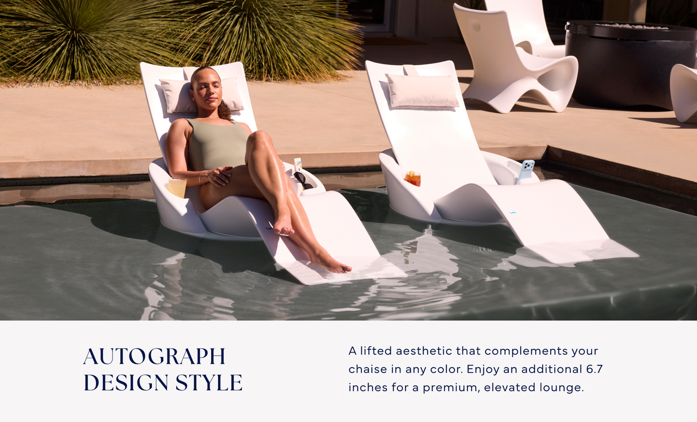 A woman enjoys a premium outdoor experience on the Ledge Lounger Autograph Chaise Armrest Console, set on the tanning ledge beside a matching empty chaise. The scene highlights modern, elevated poolside lounging.
