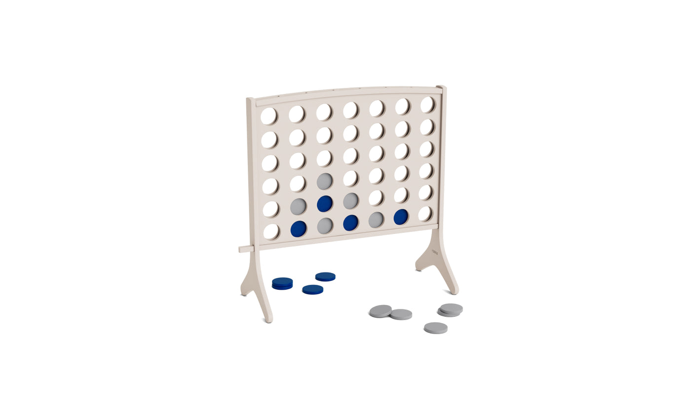 A white Ledge Lounger Four In A Row game stands upright, featuring several blue and gray checkers inside and a few checkers scattered on the ground nearby.