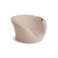 The Ledge Lounger Autograph Chaise Armrest Console is a modern beige armchair with a rounded back and smooth curves, featuring a textured finish—ideal for relaxing or socializing. It is displayed on a plain white background.