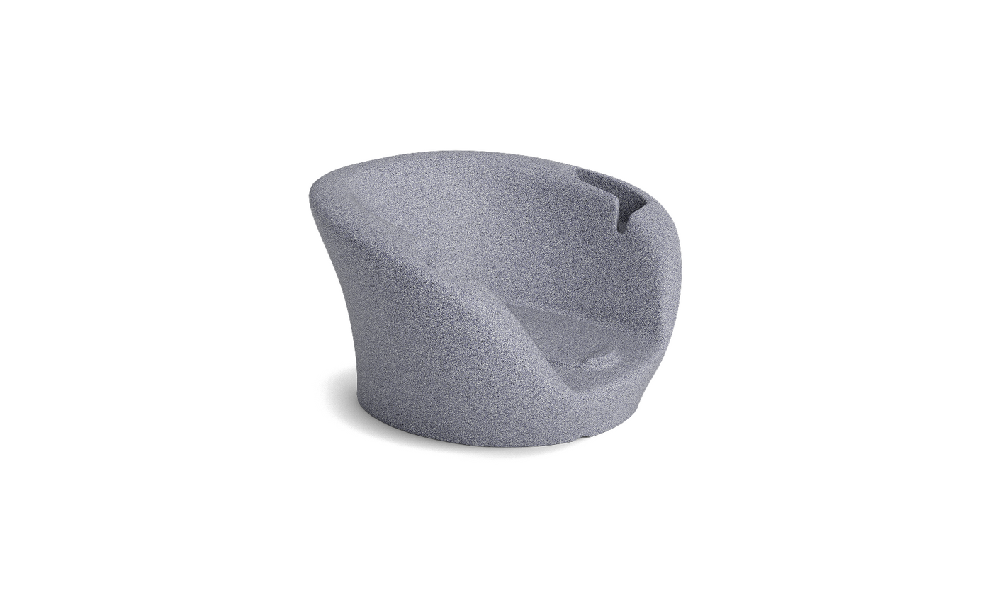 The Ledge Lounger Autograph Chaise Armrest Console features a modern, sculpted silhouette with a curved backrest and seat in textured light gray fabric, boasting seamless lines for stylish relaxation or socializing. Displayed on a white background.