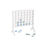 The Ledge Lounger Four In A Row is a white vertical game board with alternating light blue and green discs placed inside, and several discs resting on the nearby surface. This oversized outdoor game features an all-weather design, making it the perfect giant Four In A Row experience for backyard gatherings.