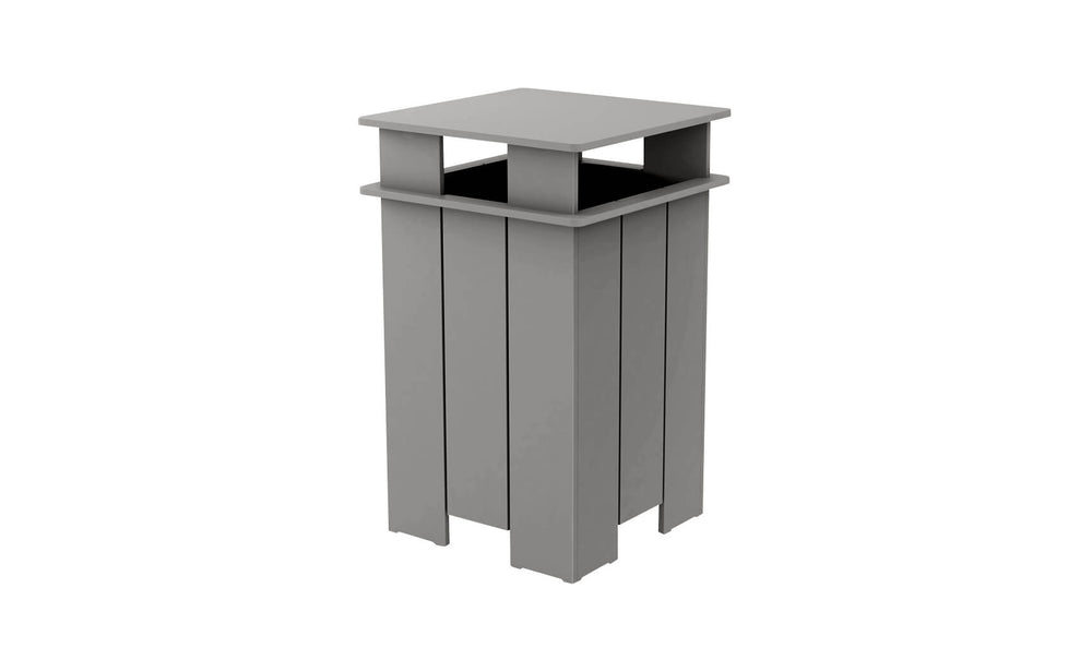 The Mainstay Trash Bin by Ledge Lounger is a tall, rectangular, gray outdoor trash can. It features a flat top and open sides with vertical slats in a modern, minimalist design. Crafted from UV stable materials, it ensures lasting durability.