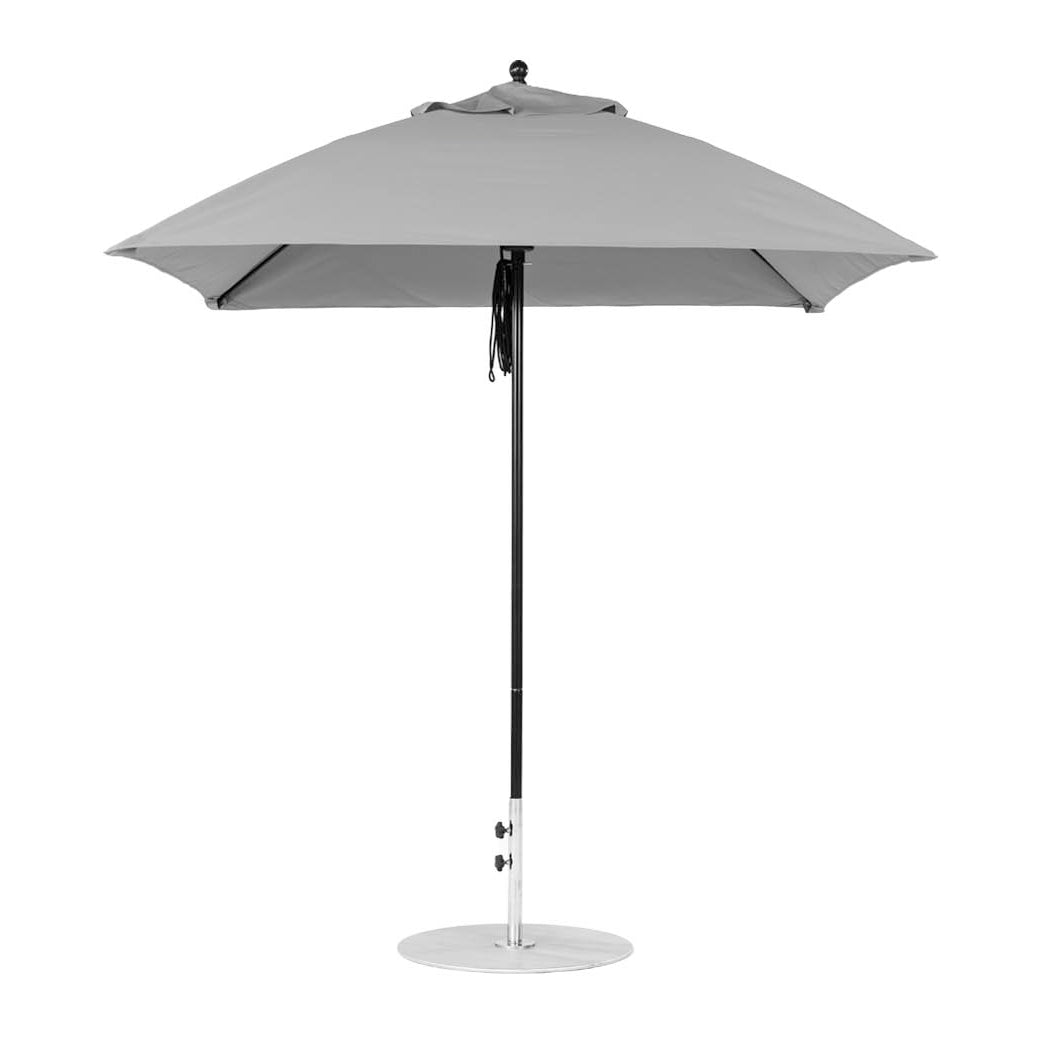 The Essential Fiberglass Umbrella by Ledge Lounger has a sleek, minimalist design with a square canopy made from marine-grade fabrics. It features a straight pole and a flat base, showcased fully open against a plain white background.