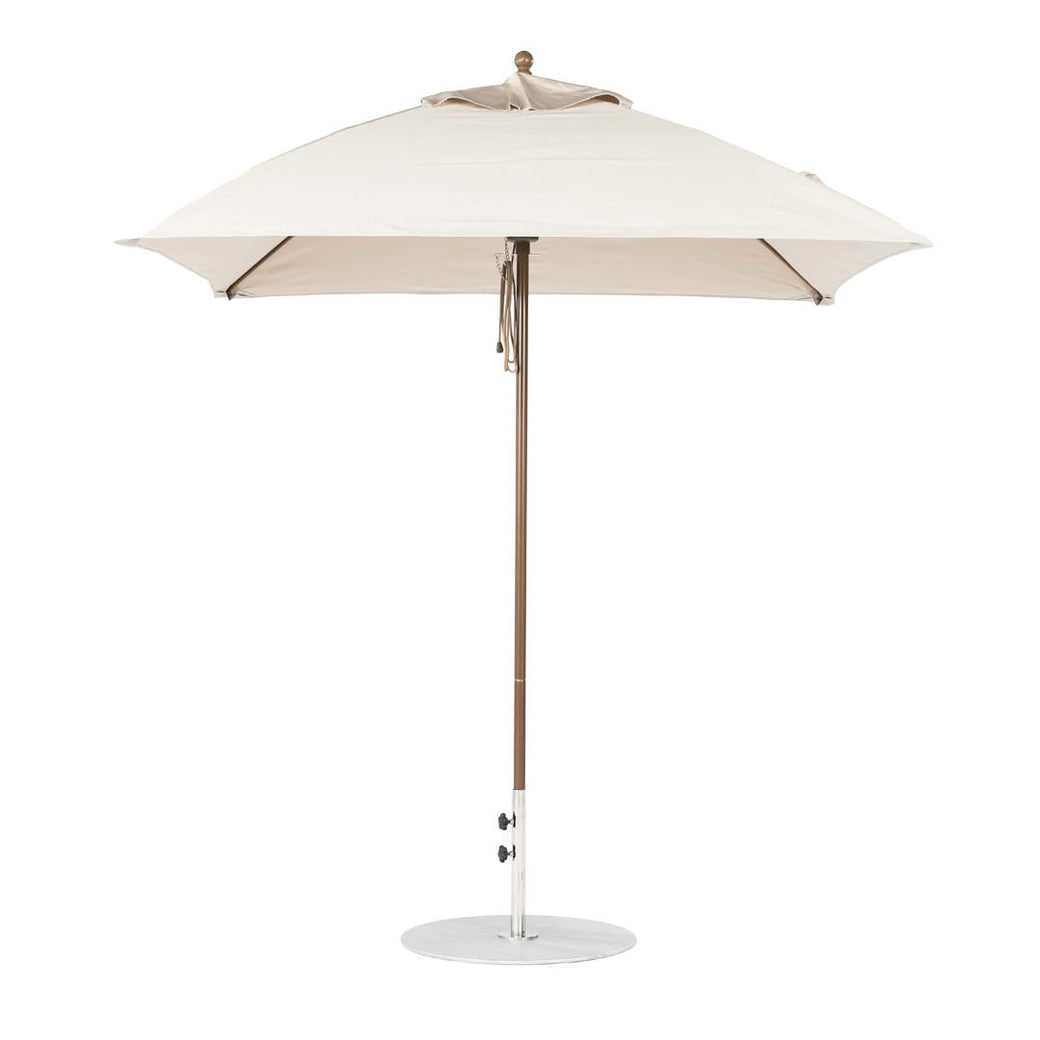 The Essential Fiberglass Umbrella by Ledge Lounger is a 7.5 square beige outdoor umbrella with a durable wooden pole and marine-grade fabrics, resting on a circular metal base, shown against a plain white background to emphasize style and durability.