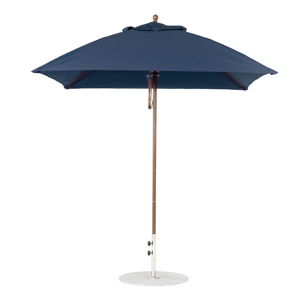 The Ledge Lounger Essential Fiberglass Umbrella features a 7.5 square canopy with marine-grade fabrics for durability, a wooden pole, and a round white base. Its stylish design offers resilience, standing fully open and upright.