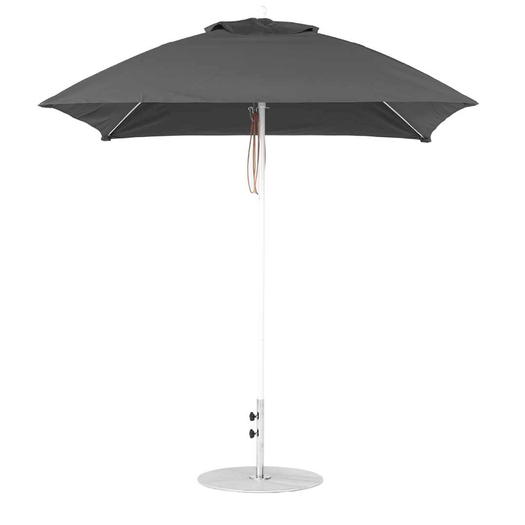The Ledge Lounger Essential Fiberglass Umbrella - 7.5 Square Pulley showcases a closed, dark gray canopy crafted from marine-grade fabrics on a tall silver pole with a round base. It includes two adjustment levers and features a tan strap against a plain white background.