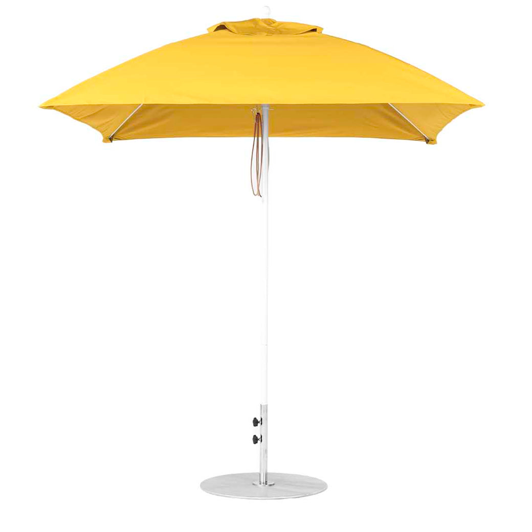 The Essential Fiberglass Umbrella by Ledge Lounger, featuring a sleek silver metal pole and round base, showcases a vibrant yellow square design with a flat top and marine-grade fabrics for lasting durability.