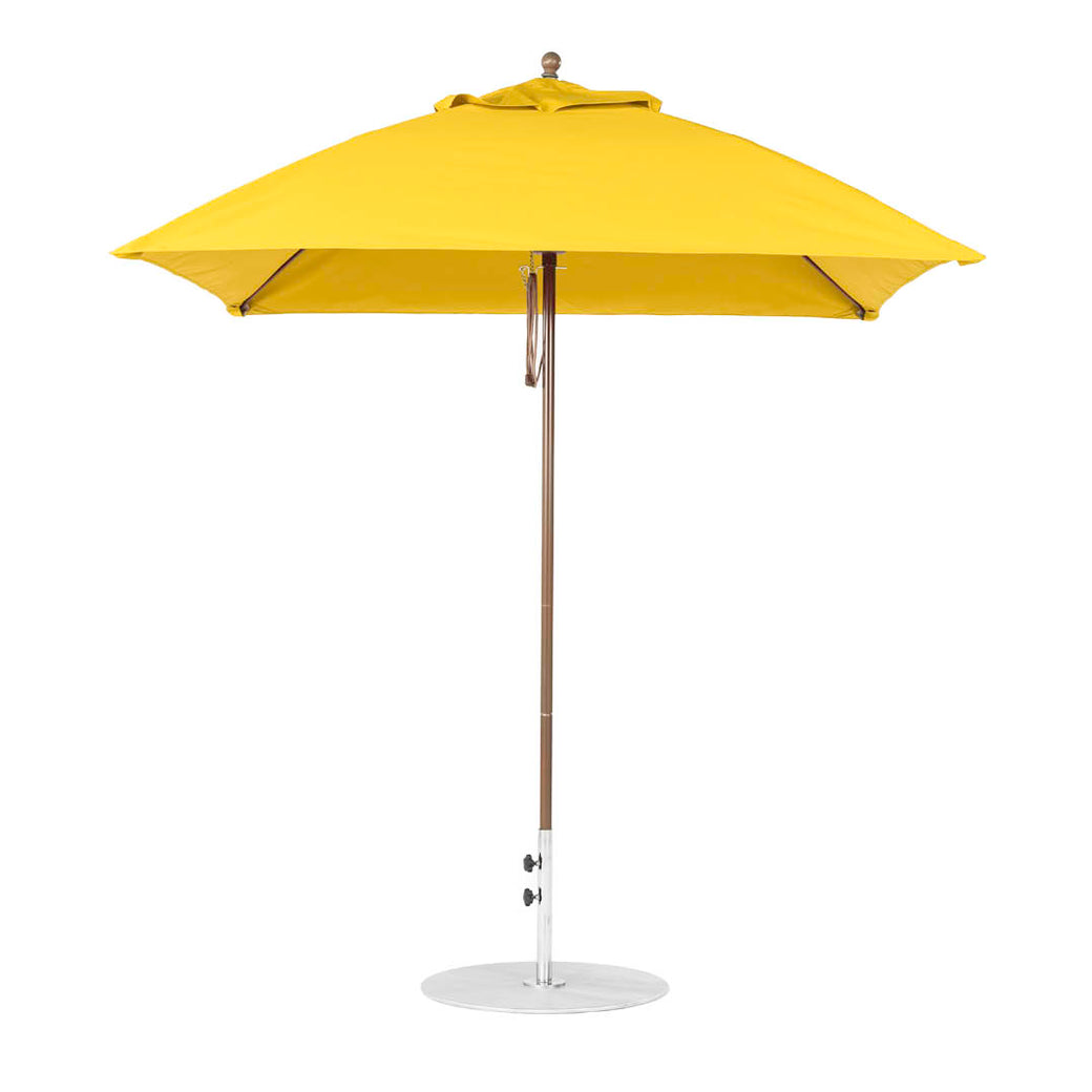 A yellow Essential Fiberglass Umbrella - 7.5 Square Pulley by Ledge Lounger features a marine-grade fabric canopy, thin silver pole, and circular base. The closed umbrella stands upright against a white background, highlighting its durable design.