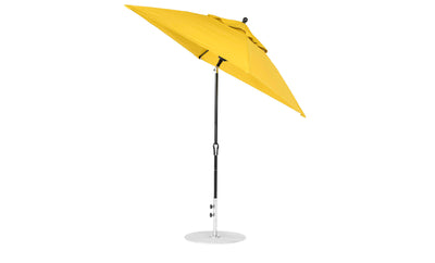 The Essential Fiberglass Umbrella by Ledge Lounger is a large, yellow 6.5 square outdoor umbrella with a metal pole on a circular base. Corrosion-resistant and featuring marine-grade fabric, it stands open with its wide canopy slightly tilted using its crank auto-tilt feature.
