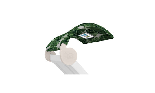 A Signature Chaise Shade from Ledge Lounger is partially covered with tropical leaf-pattern fabric in green shades, and it includes a convenient integrated control panel on one side.