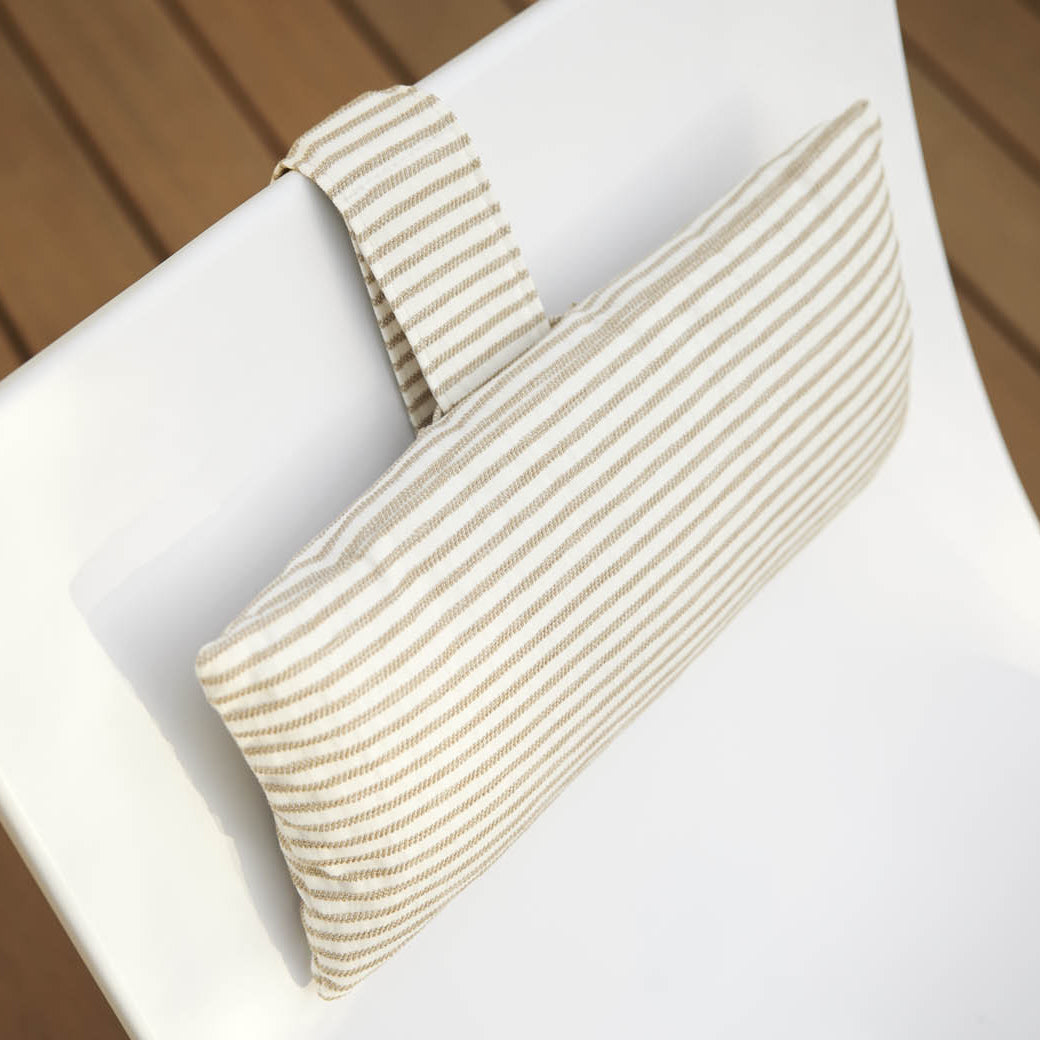 The Autograph Headrest Pillow from Ledge Lounger is a final sale item featuring a white cushion with beige and white stripes, designed to attach securely to a chair backrest via a loop.