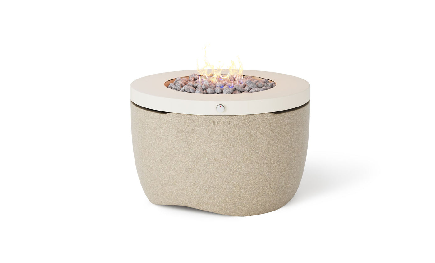 The Halo Firepit by Ledge Lounger is a beige, round propane fire pit featuring a smooth, modern design with a concrete-like texture. Its circular opening is filled with small stones where a gentle flame dances above, creating an inviting outdoor ambiance.