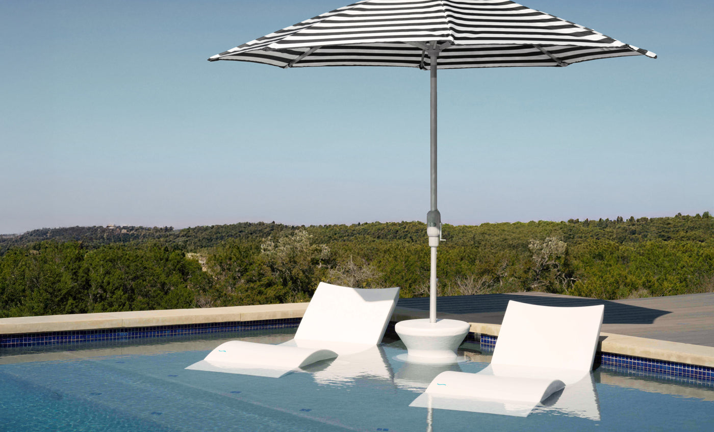 The Ledge Lounger Signature Chaise and Side Table with Umbrella In-Pool Set offers a stylish spot in shallow water, featuring a black-and-white umbrella with scenic views—ideal for relaxing poolside.