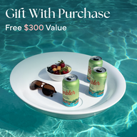A floating tray in a pool holds Test Product for Transaction Test by Ledge Lounger, berries, and sunglasses. Text above reads Gift With Purchase, Free $300 Value. Sunlight sparkles on the clear blue water.