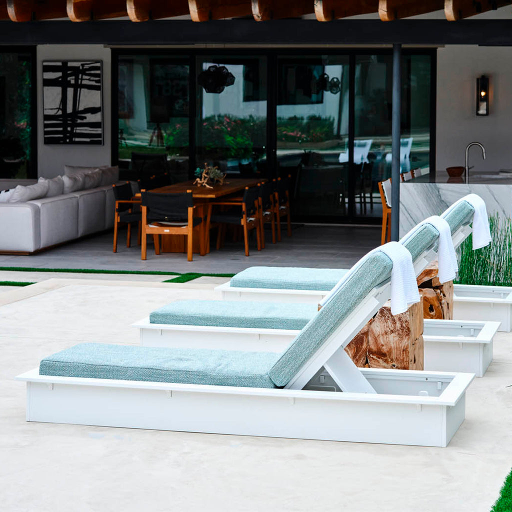 Outdoor dining area with white lounge beds and a poolside perspective