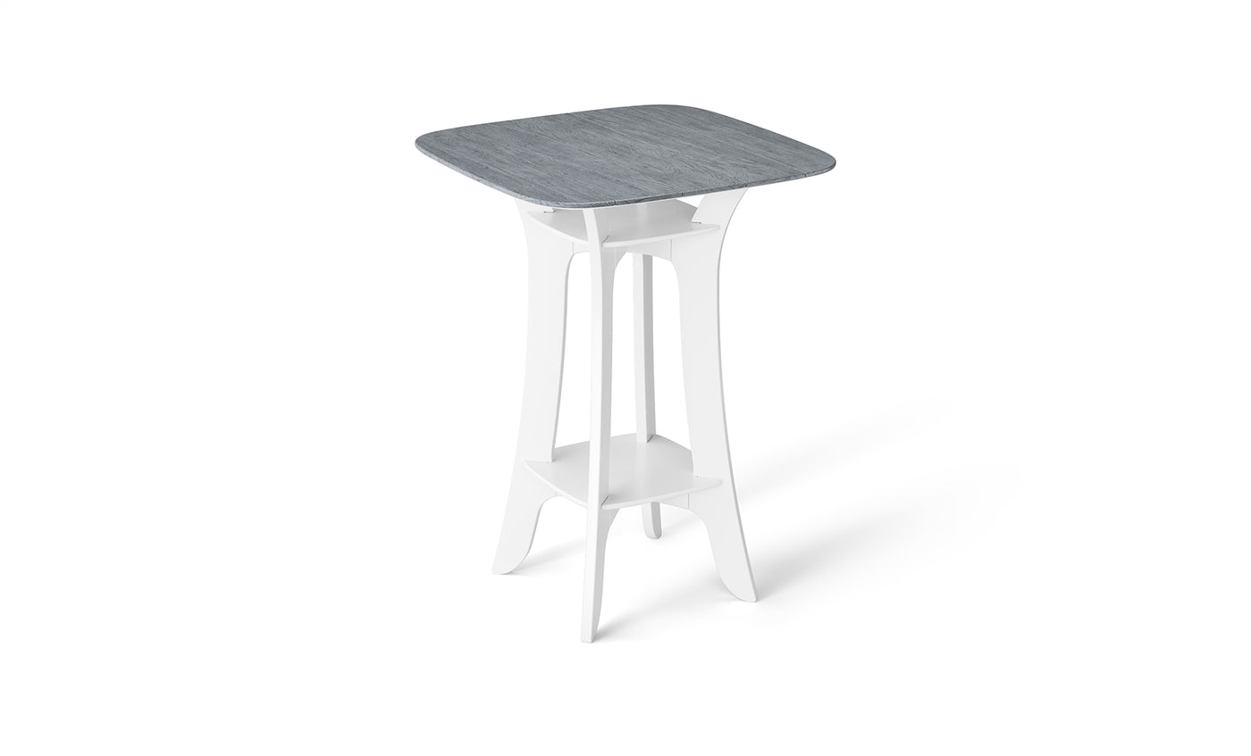 The Haven Hightop Table by Ledge Lounger features a square, light blue-grey tabletop with a white, modern base, curved legs, and a lower shelf. Its durable, minimalist design is contemporary and perfect for any patio collection.