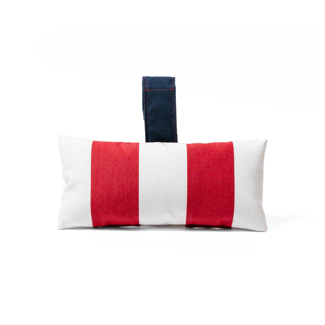 The Autograph Headrest Pillow by Ledge Lounger features red and white vertical stripes with a dark blue handle. Made from marine-grade fabric, its ideal for in-pool relaxation against a plain white background.