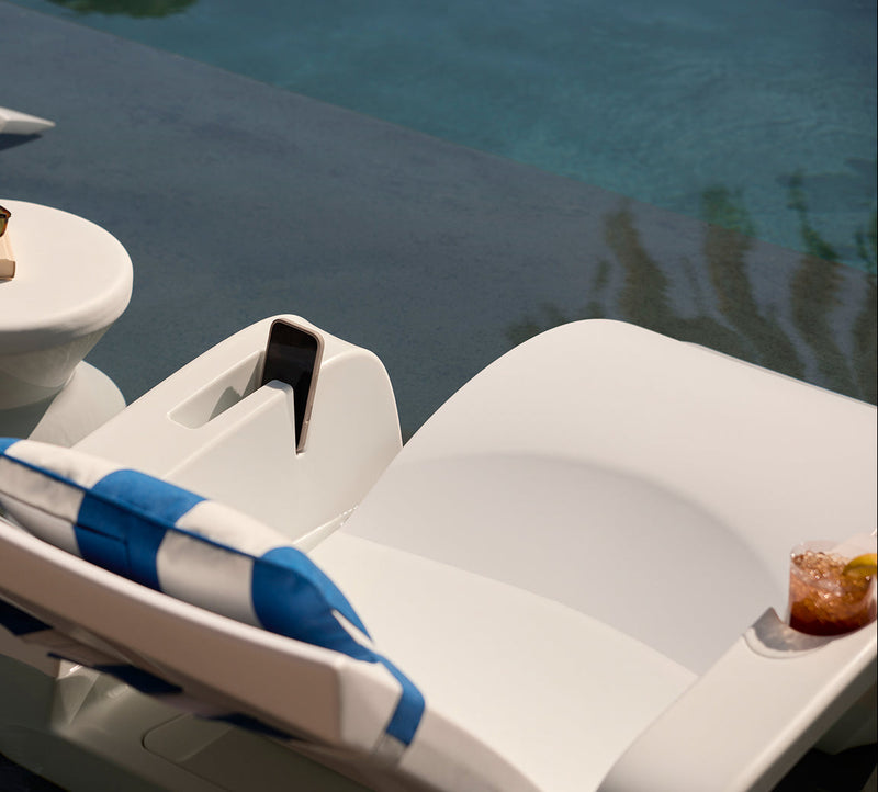 White lounge chair with blue towel by a poolside
