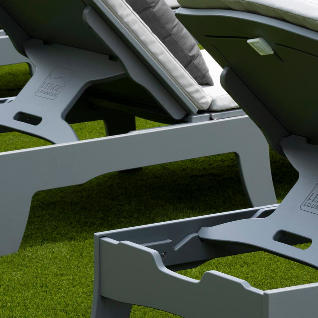 Close-up of the side frame and mechanism of a gray adjustable chaise lounge.
