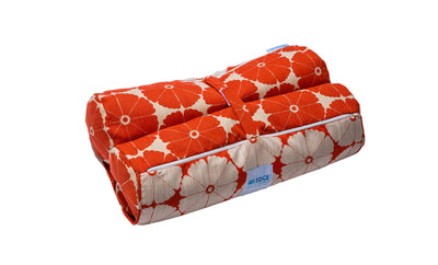 The Laze Hammock yoga mat bag from Ledge Lounger, featuring a red floral quilted design with white flowers and a blue label, is perfect for outdoor adventures. Made from marine-grade fabrics, it includes a convenient handle and rolls up securely with a strap.