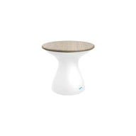 The Autograph Standard Side Table by Ledge Lounger features a smooth, white hourglass-shaped base and a flat, light wood top. This modern minimalist stool doubles as an outdoor side table, perfect for contemporary flair and poolside storage needs.