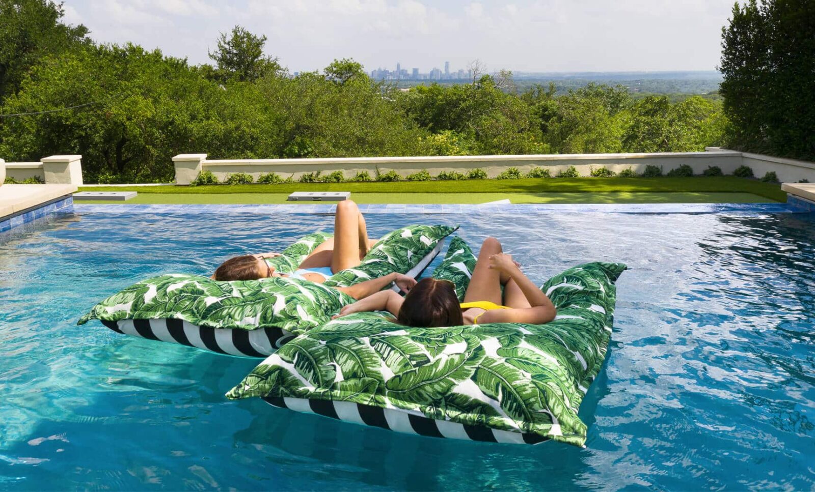 Two people laying on Ledge's jungle floating pillows