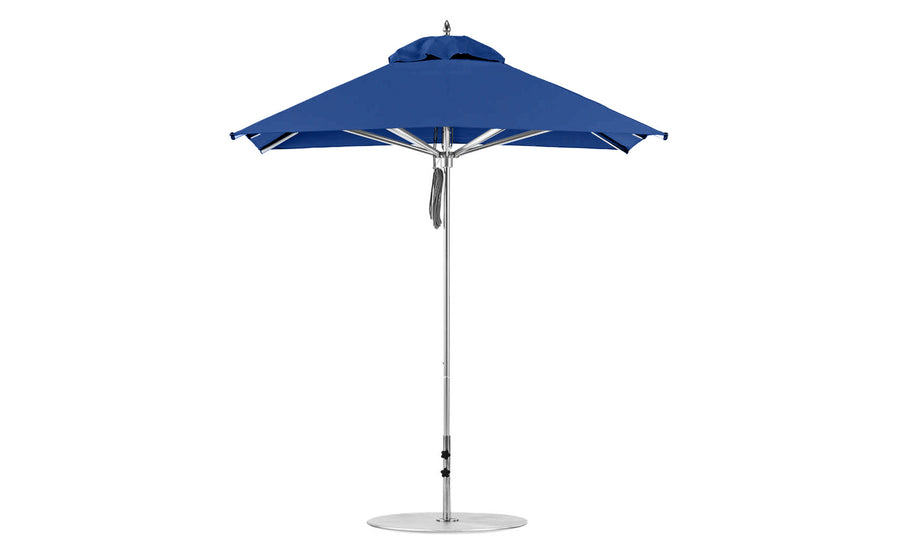 The Premier Aluminum Umbrella by Ledge Lounger features a tall, blue design with a central metal pole and round base. It boasts neatly gathered fabric and securing straps when closed. Its modern square shape is perfect for outdoor use.