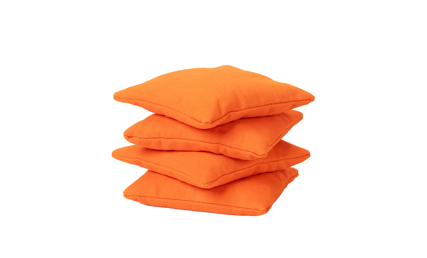 Four Ledge Lounger Bean Bags, set of four in bright orange, are stacked neatly on top of each other against a plain white background, showcasing their premium quality and durability.
