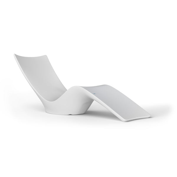 A modern, minimalist white chaise lounge with a sleek, curved design. The chair features a high backrest and an extended leg rest, all in a smooth, single-piece construction. It is set against a plain white background.