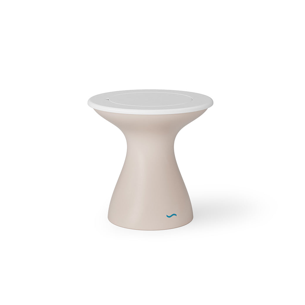 The Autograph Tall Ice Bin Side Table by Ledge Lounger is a beige, hourglass-shaped stool with a modern design and round white top, perfect as an outdoor side table. A small blue logo at the bottom adds charm against the white backdrop.