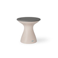 The Autograph Tall Ice Bin Side Table by Ledge Lounger is a modern, hourglass-shaped stool that also serves as a chic outdoor side table. It features a beige body, flat round gray top, and sleek minimalist design with a small blue logo near the base.
