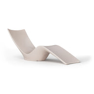 The Autograph Chaise by Ledge Lounger, with its sleek minimalist design, features a high backrest and extended leg support in beige. It sits elegantly against a white background, ideal for both indoor and outdoor lounging.