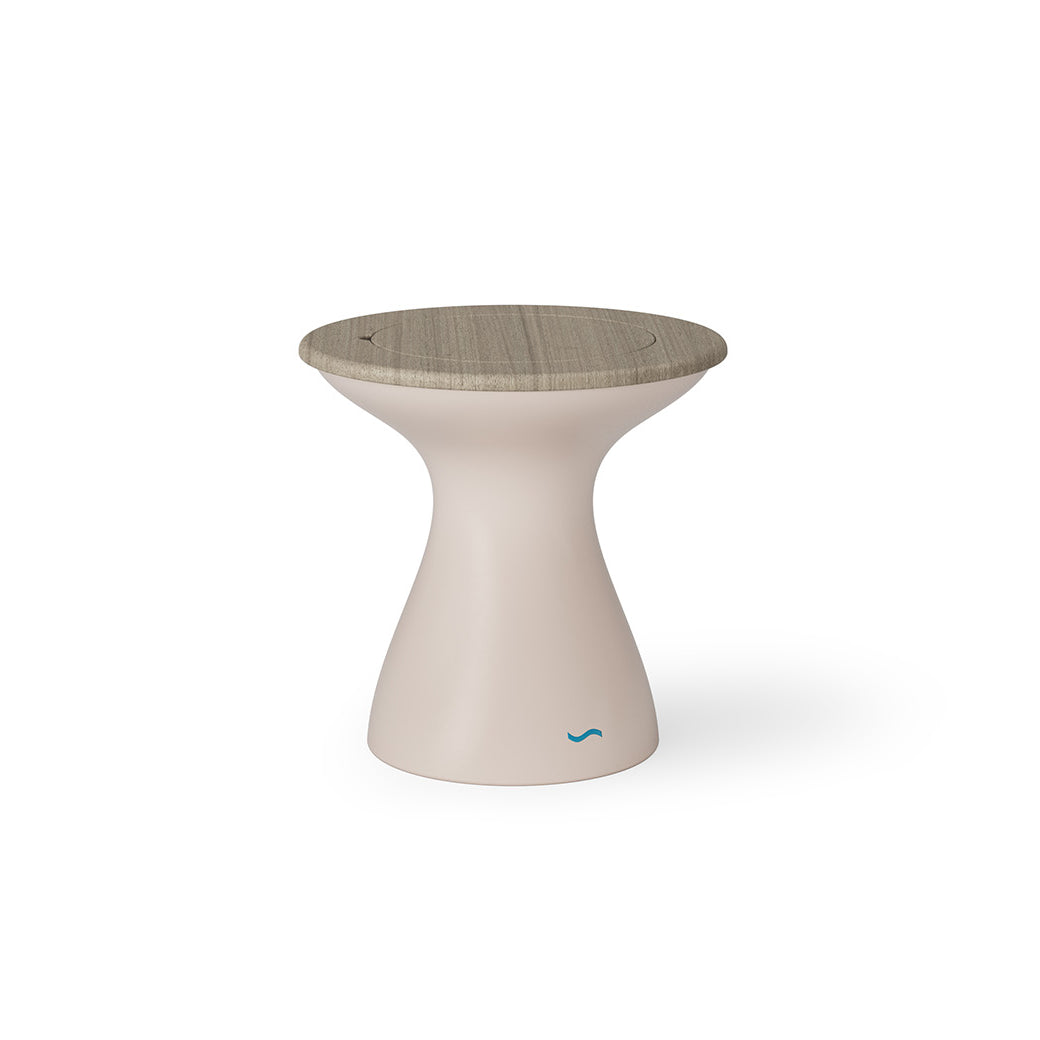 The Autograph Tall Ice Bin Side Table by Ledge Lounger features a modern, hourglass design with a beige body and textured wooden top. A small blue wave logo adorns the base, making it versatile for any setting, from a white background to seamlessly blending into your patio decor.