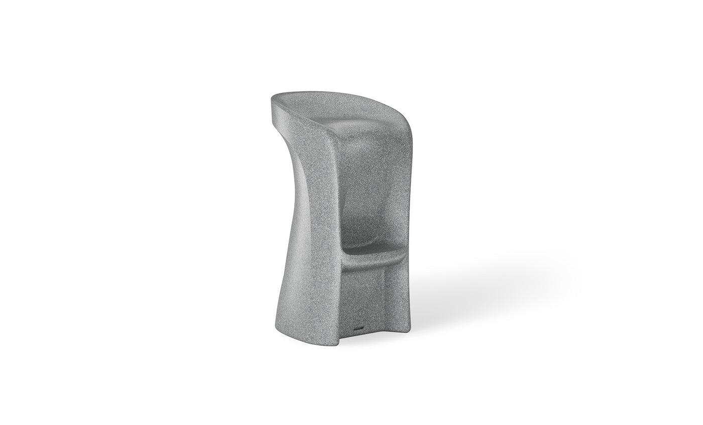 The Signature Barstool Bar Height by Ledge Lounger is a gray, modern high chair ideal for outdoor entertaining. It features a smooth design with an integrated backrest and footrest, crafted from weatherproof material with an asymmetric shape on a sturdy base, perfect for pool bar settings.