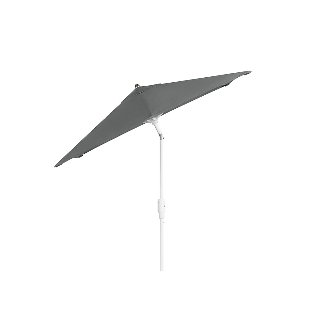 A gray, triangular 6.5 Square Signature 360° Tilt Umbrella by Ledge Lounger with a rustproof frame and white pole stands slightly tilted against a plain white background.