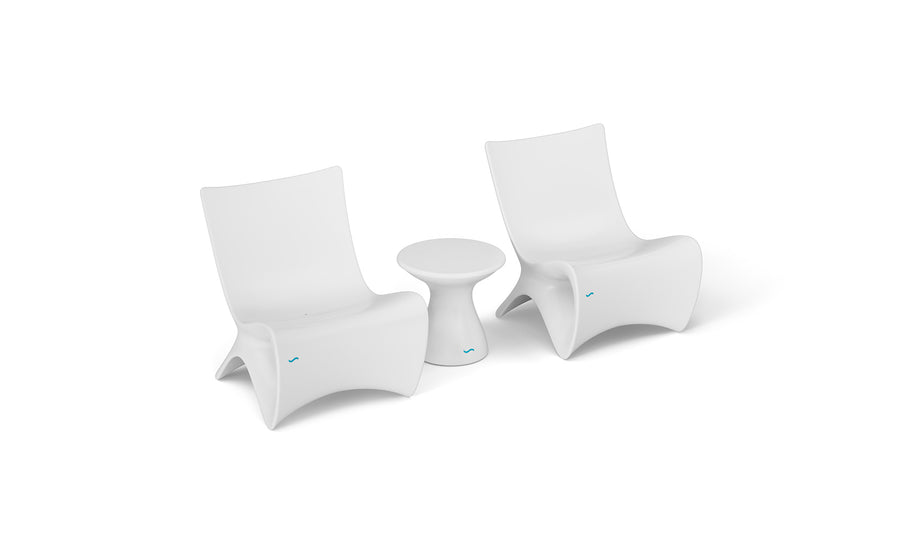 Two Classic Luxury In-Pool Chair Duo from Ledge Lounger, featuring sleek curved designs in modern white, stand beside a petite round side table. Set against a plain white backdrop, this arrangement creates a minimalist and contemporary atmosphere.