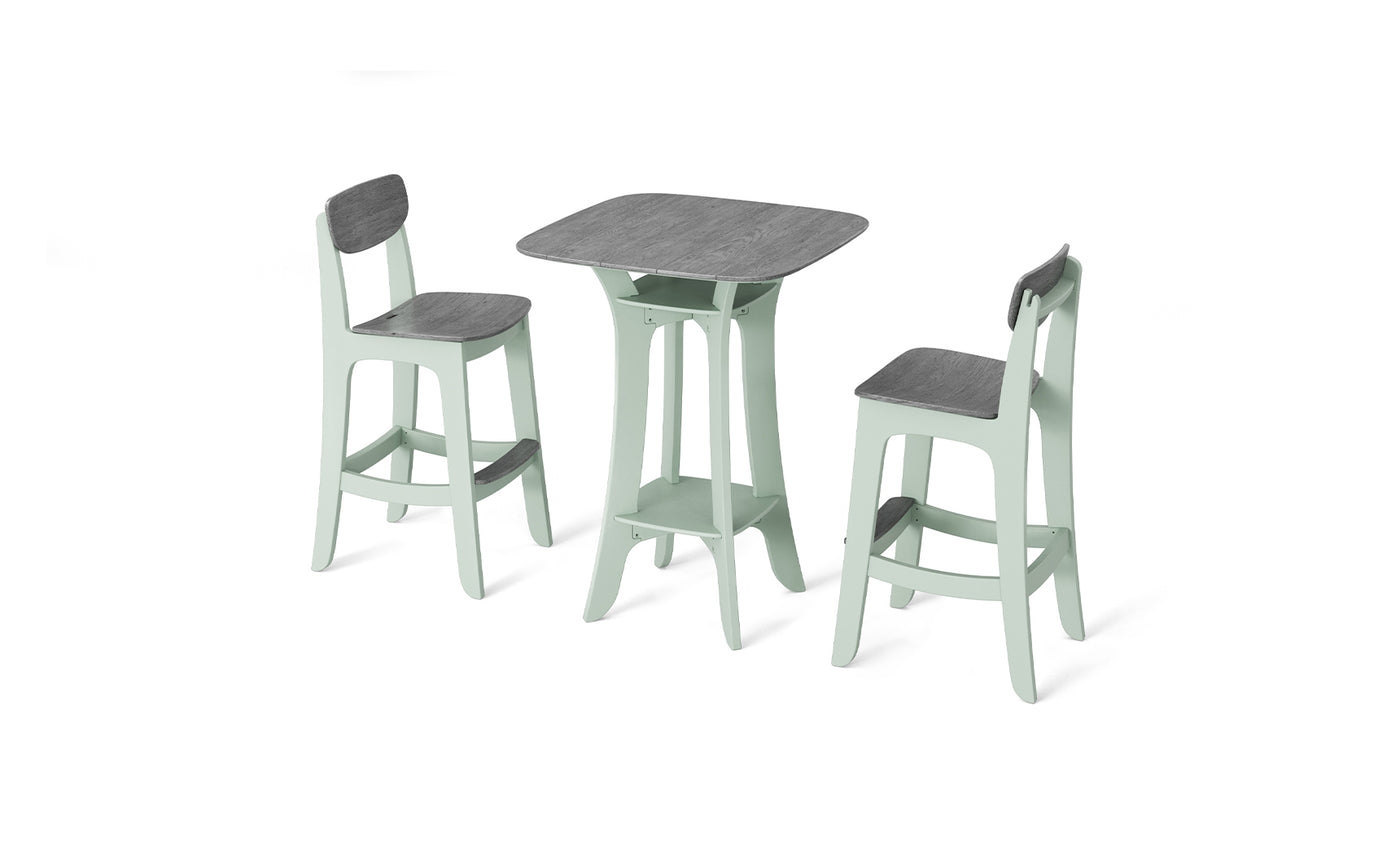 The Haven Hightop Set by Ledge Lounger includes a small dining table with a square dark wood tabletop and mint green frames, paired with two Haven stools. Its simple and modern design stands out against the white background.