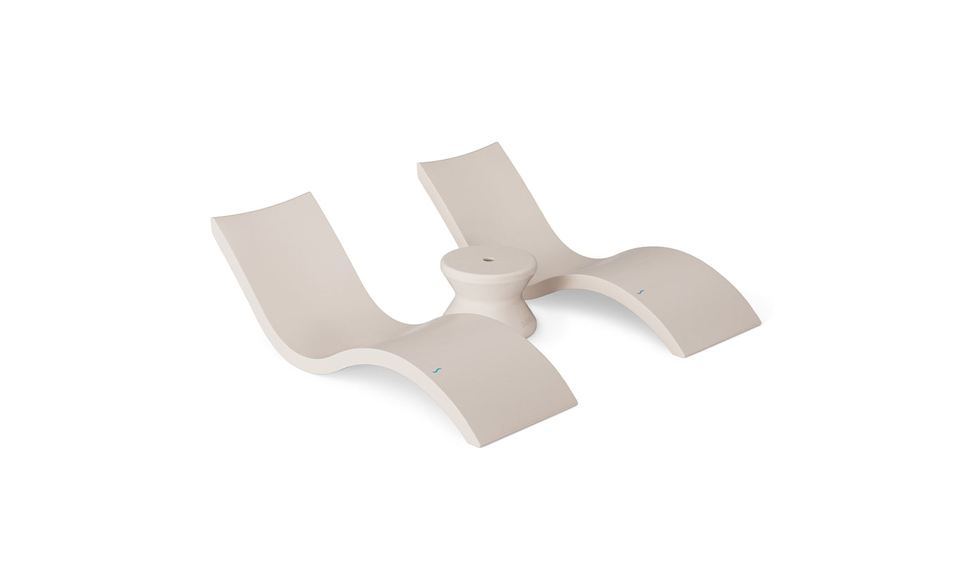 The Ledge Lounger Outdoor Oasis In-Pool Furniture Bundle includes a modern, sculptural beige lounge chair featuring two curved seats on a circular base. Its sleek design with smooth surfaces and minimalist lines is ideal for creating an artistic outdoor retreat.