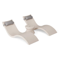 The Ledge Lounger Signature Chaise Headrest Pillow and Side Table In-Pool Set features two modern beige chaise loungers with gray headrest pillows, connected by a round center table, all styled for poolside chic against a white background.