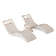 The Ledge Lounger Signature Chaise Headrest Pillow and Side Table In-Pool Set features two modern beige loungers with white pillow headrests, joined by a round side table—ideal for relaxing poolside or creating an outdoor oasis. Plain white background.
