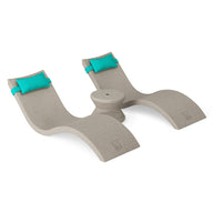 The Ledge Lounger Signature Chaise Headrest Pillow and Side Table In-Pool Set features two beige curved loungers with built-in aqua blue headrests connected by a round side table, ideal for enhancing your outdoor paradise. Shown on a plain white background.
