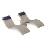 Experience ultimate relaxation in your outdoor paradise with the Ledge Lounger Signature Chaise Headrest Pillow and Side Table In-Pool Set—two curved chaise loungers with dark blue headrest pillows and a circular side table, all in a smooth beige wave-like design.