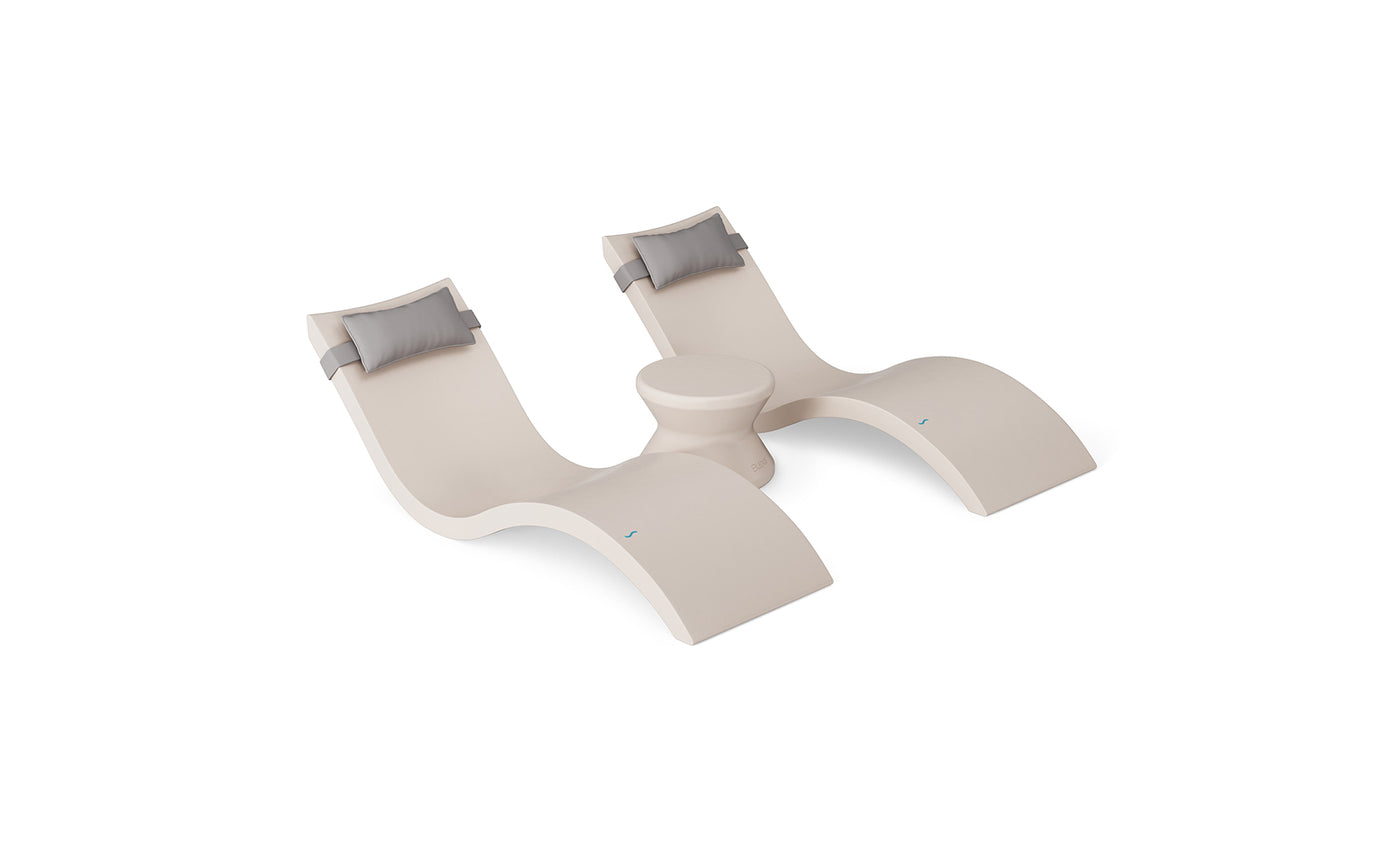 The Ledge Lounger Signature Chaise Headrest Pillow and Side Table In-Pool Set features two modern beige chaises with gray headrest pillows and a matching round side table, offering sleek, comfortable poolside seating against a white background.