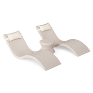 The Ledge Lounger Signature Chaise Headrest Pillow and Side Table In-Pool Set features two modern beige loungers with headrests and a round table, creating a stylish outdoor retreat perfect for relaxing poolside on a plain white background.