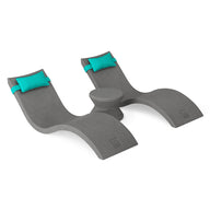 The Ledge Lounger Signature Chaise Headrest Pillow and Side Table In-Pool Set features two modern gray chaises with turquoise pillows and a round table—ideal for lounging poolside or creating an outdoor retreat, shown on a white background.