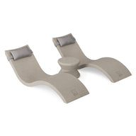 The Ledge Lounger Signature Chaise Headrest Pillow and Side Table In-Pool Set features two beige, curved loungers with headrests and a small circular table, offering a modern, minimalist poolside seating solution.