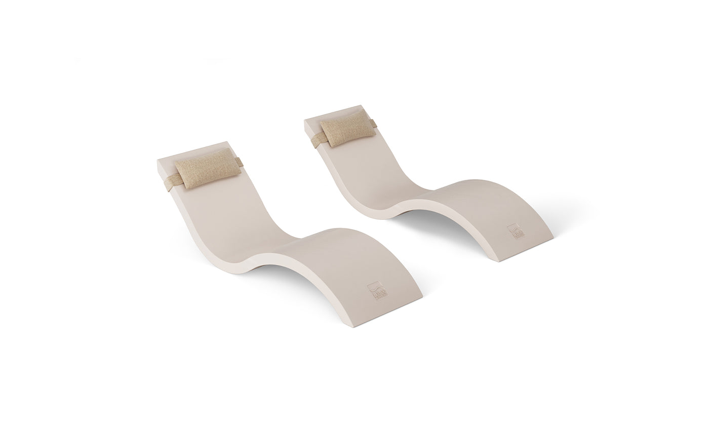 The Outdoor Escape In-Pool Furniture Bundle by Ledge Lounger includes two modern, curved beige lounge chairs with integrated headrest pillows. These chairs feature a sleek, minimalist design and wave-like structure, beautifully complementing a white background.