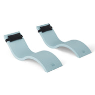 Two light blue curved ergonomic footrests by Ledge Lounger, resembling a Signature Chaise and featuring black straps, enhance comfort with adjustable support for feet and legs. Ideal for your Outdoor Escape In-Pool Furniture Bundle, they rest on a white surface in a wave-like design.